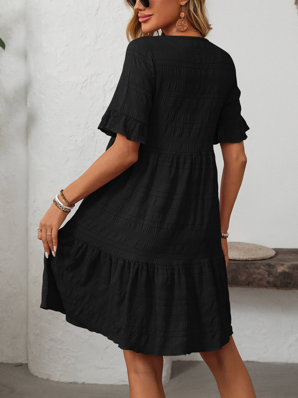 Margo & Main – Vianne black textured tiered short-sleeve dress, front view of the tiered hem with hands at the sides, US women's sizes
