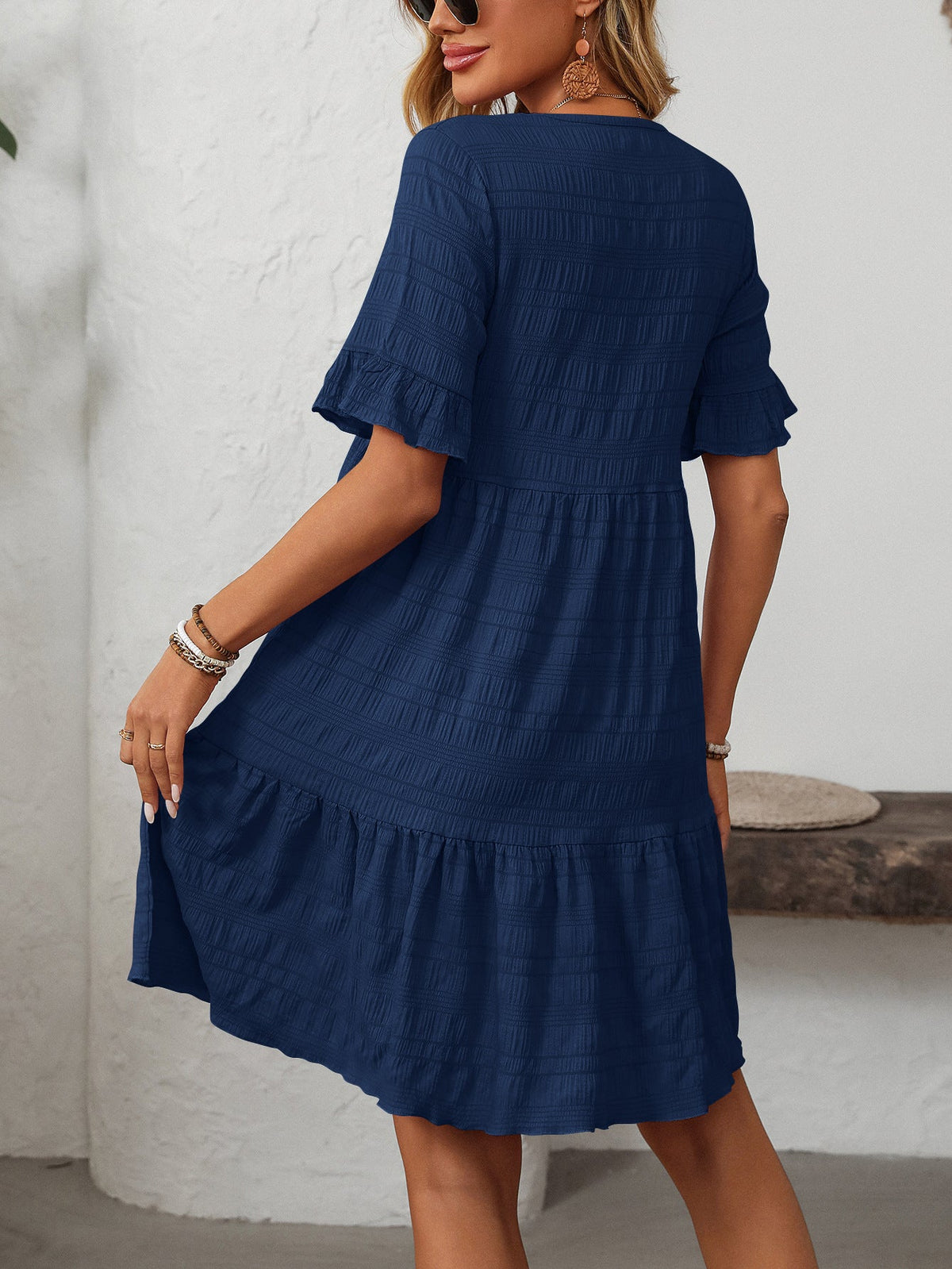 Margo & Main – Vianne navy blue textured tiered short-sleeve dress, front view of the tiered hem with hands at the sides, US women's sizes