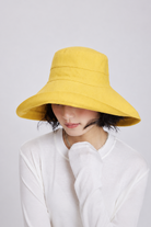 Margo & Main – Elke yellow wide-brim foldable sun hat seen from a three-quarter angle, showing the seamed crown and self-fabric band