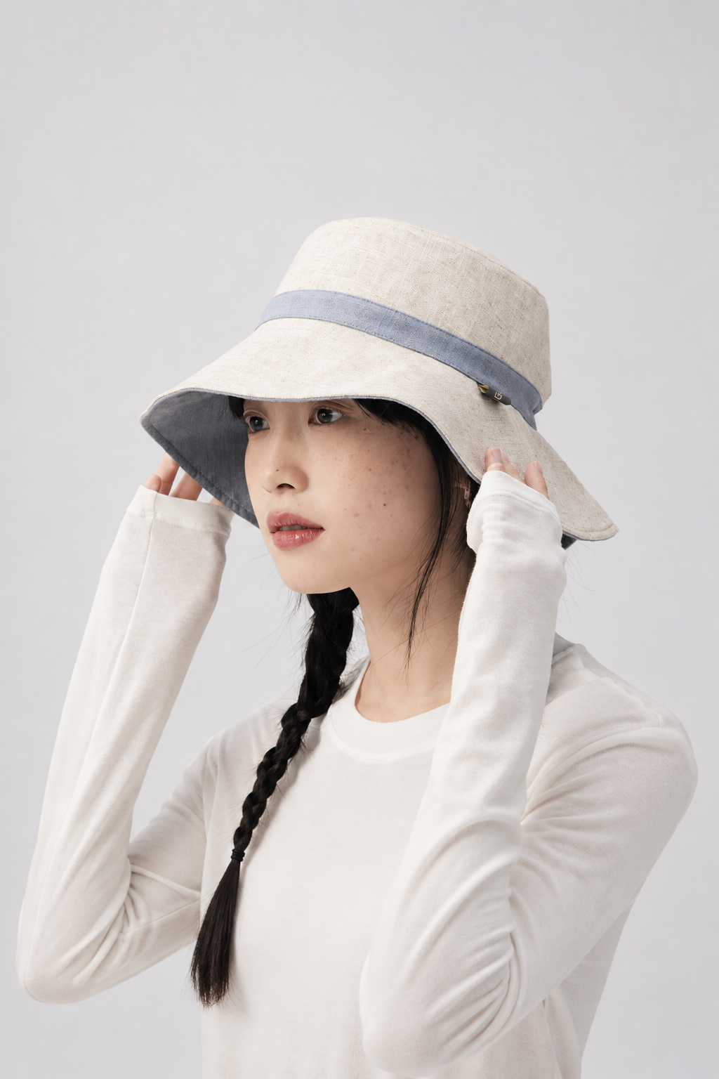 Margo & Main – Sabella reversible sun hat turned to its natural linen side with a blue band, side view on model