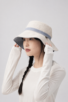 Margo & Main – Sabella reversible sun hat turned to its natural linen side with a blue band, side view on model